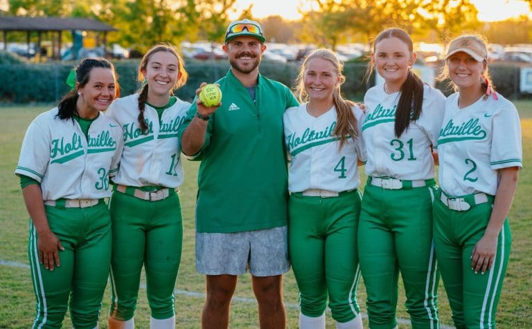 Coach Reese Claybrook, center, holds the game ball commemorating his 100th career win, surrounded by six of his Holtville players after the milestone victory in April 2024. (Photo submitted)