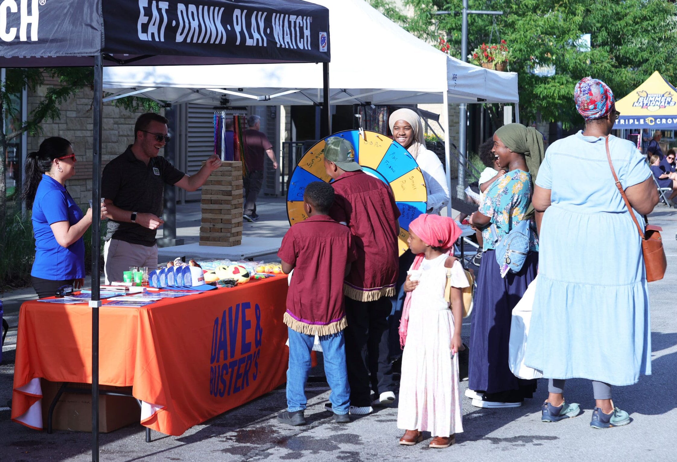 Families visit vendor booths and activity stations during the Midwest Summer Nationals player festival.